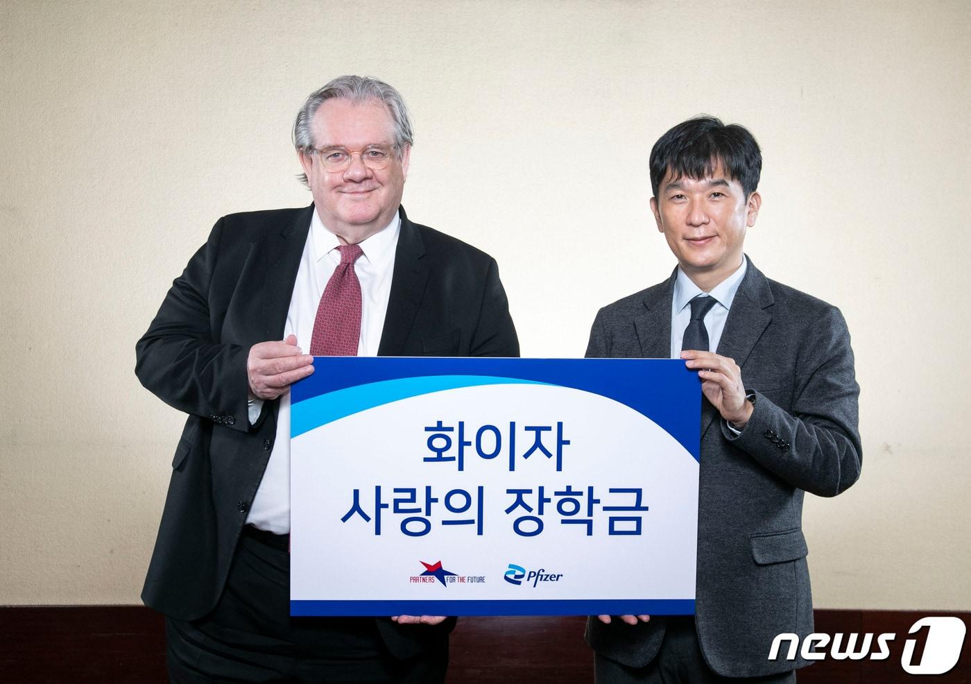 한국화이자제약 오동욱 대표이사 사장(오른쪽)이 미래의동반자재단 제프리 존스 이사장에게 ‘화이자 사랑의 장학금’을 전달하고 있다. (화이자 제공)/뉴스1