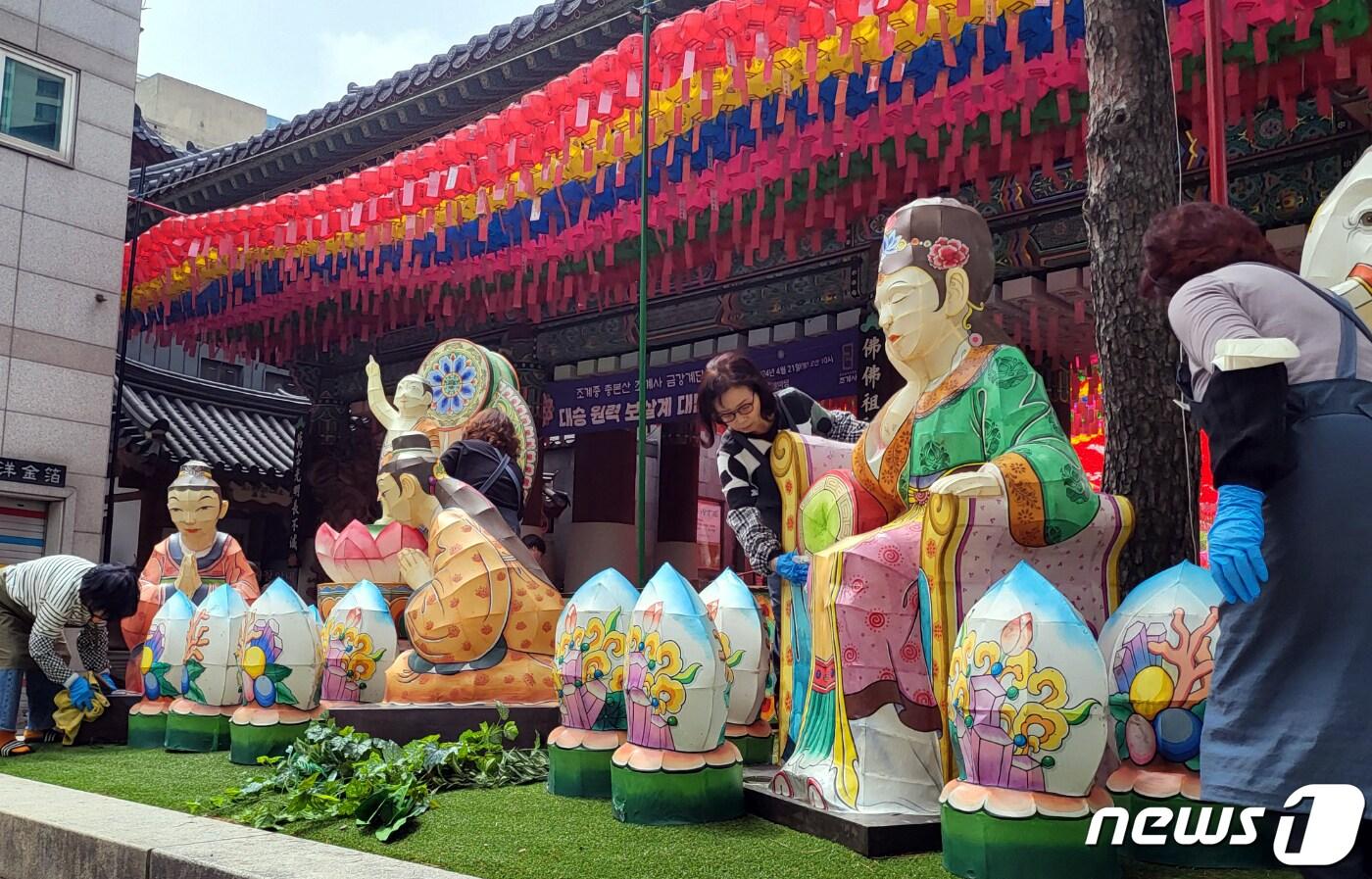 본문 이미지 - 부처님 오신날을 한 달여 앞둔 16일 오후 서울 종로구 조계사 일주문 앞에서 불자들이 조형물을 닦고 있다. 2024.4.16/뉴스1