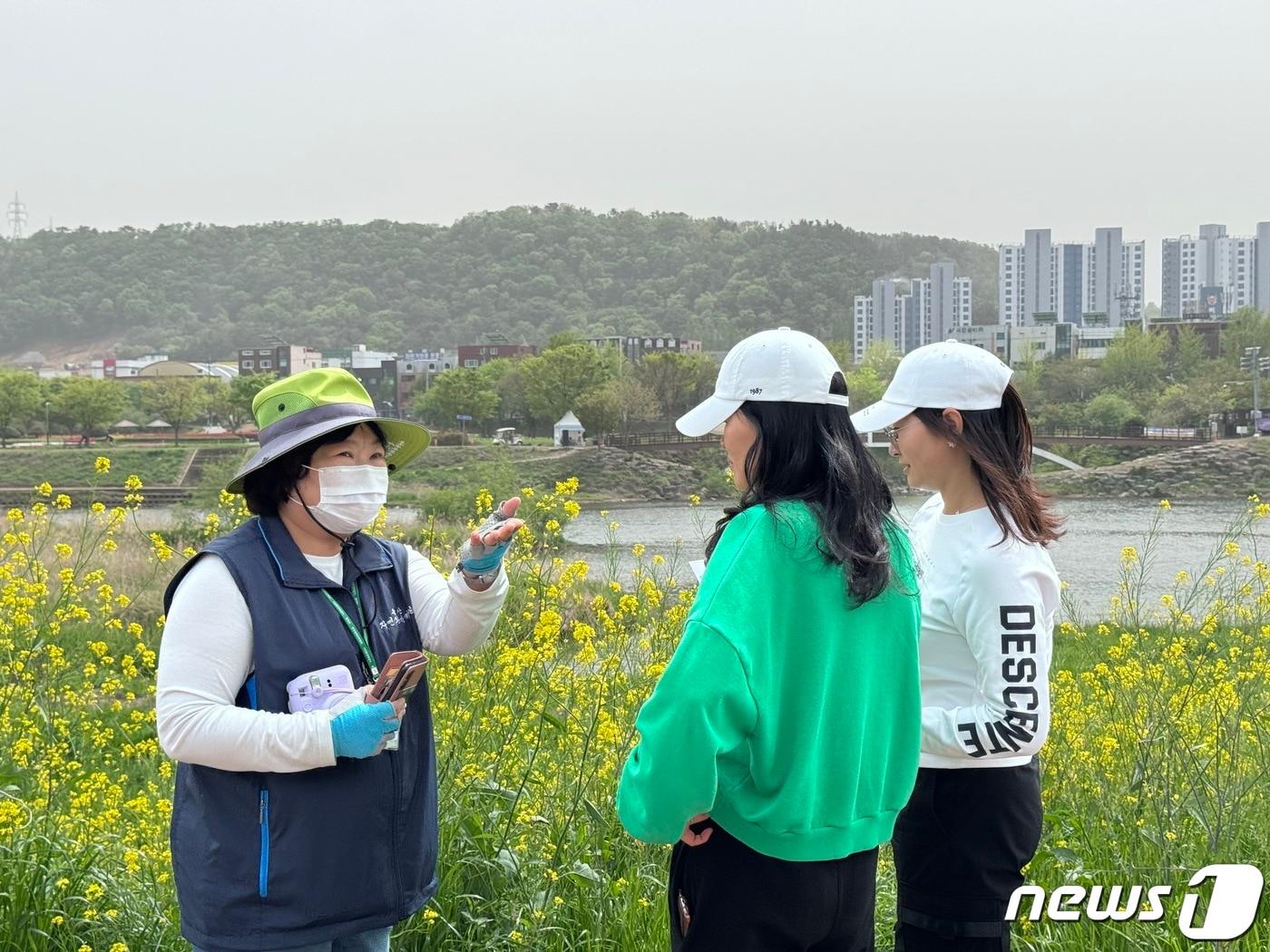 본문 이미지 - 17일 울산 태화강변에 마련된 태화강 야생 갓꽃 생태 관찰장에서 김영희 자연환경해설사가 시민들에게 태화강변에 핀 야생 갓꽃에 대해 설명하고 있다. 2024.4.17/뉴스1 ⓒ News1 김세은 기자
