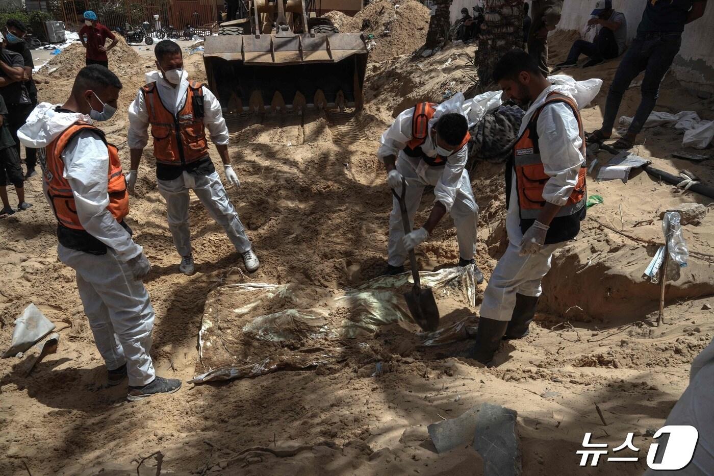 4월23일(현지시간) 보건 요원들이 가자지구 남부 칸 유니스의 나세르 의료단지에 매장된 시신들을 수습하고 있다. ⓒ AFP=뉴스1