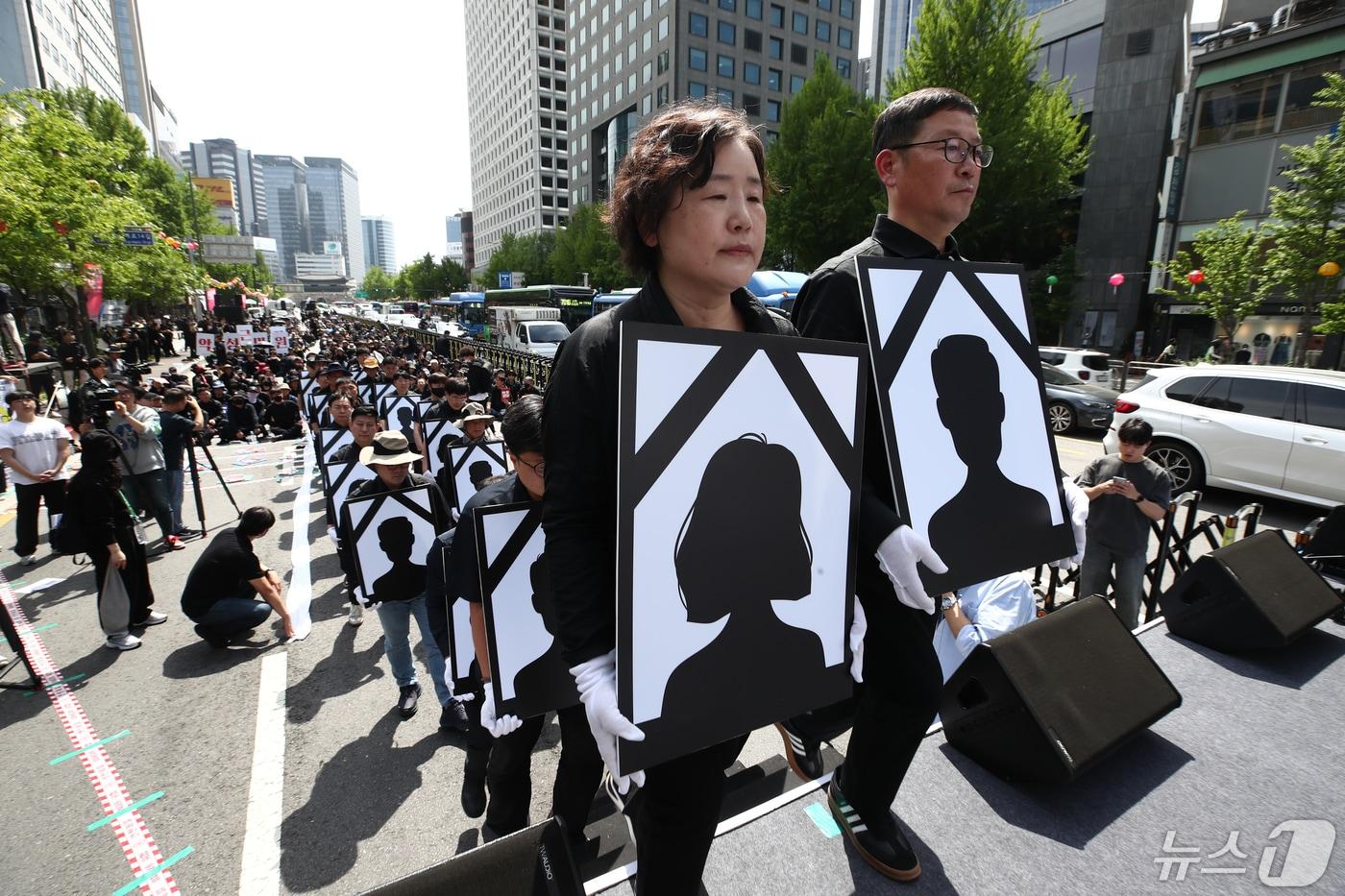 본문 이미지 - 29일 오후 서울 태평로에서 전국공무원노조와 대한민국공무원노조 주최로 열린 '악성 민원 희생자 추모 공무원노동자대회'에서 참가자들이 영정을 들고 단상에 오르고 있다. 2024.4.29/뉴스1 ⓒ News1 이광호 기자