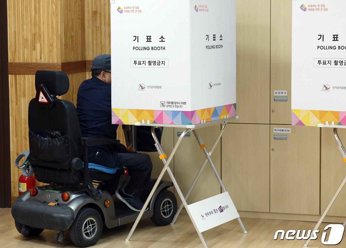 본문 이미지 - 5일 오전 서울 광진구 구의1동 주민센터 사전투표소에서 전동 휠체어를 탄 유권자가 소중한 한 표를 행사하고 있다. 2024.4.5/뉴스1 ⓒ News1 박정호 기자