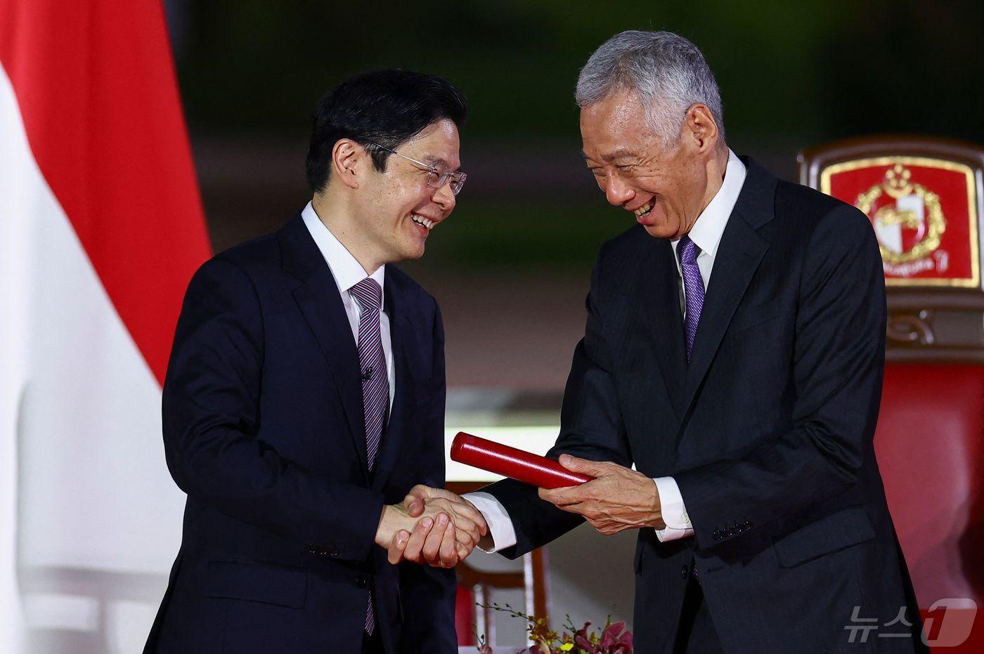 리셴룽 싱가포르 총리가 15일 사임하면서 새로 총리에 취임한 로런스 웡(황쉰차이) 총리와 악수를 나누고 있다. 2024.5.15 ⓒ AFP=뉴스1 ⓒ News1 강민경 기자