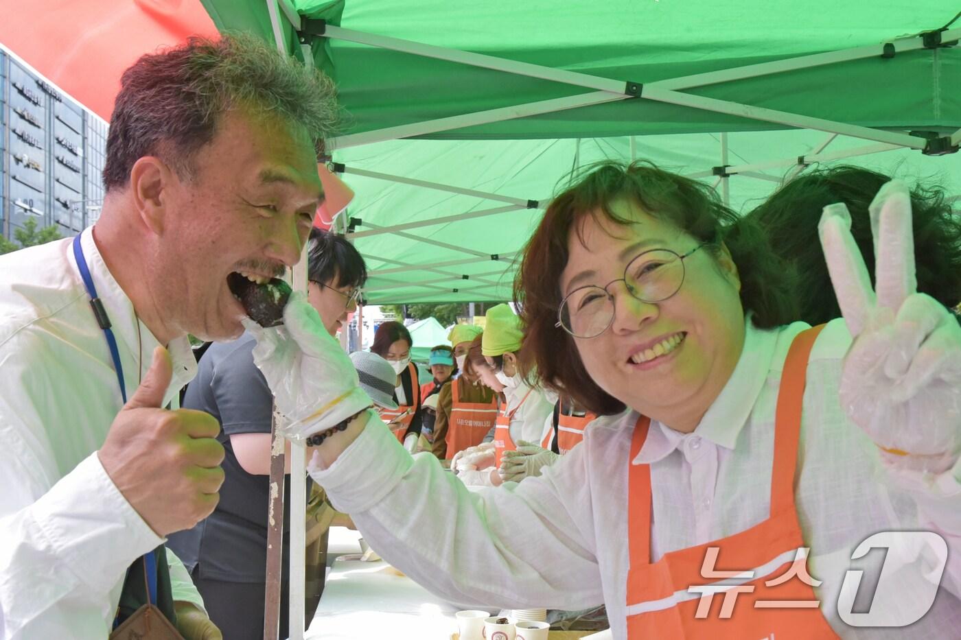 본문 이미지 - 김형미 오월어머니집 관장(오른쪽)이 17일 광주 금남로에서 열린 제44주년 5·18민주화운동 시민난장에서 야마다 히로끼 일본 우타고에 운동 단체 사무처장에게 주먹밥을 먹여주고 있다.2024.5.17/뉴스1 ⓒ News1 김동수 기자
