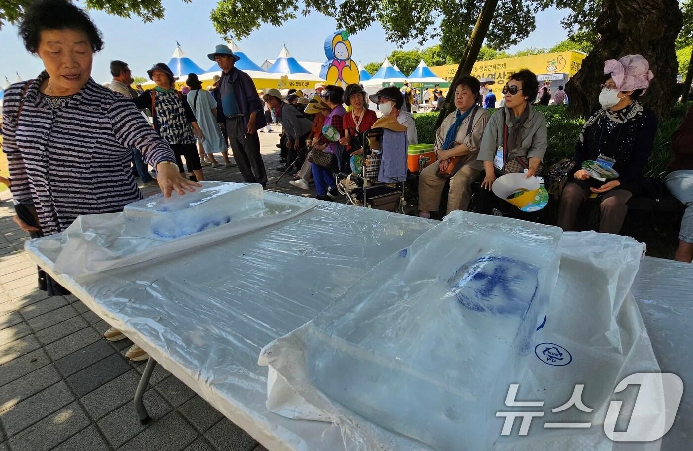 본문 이미지 - '2024 성주생명·참외문화축제가 열린 18일 성주지역 낮 최고기온이 29.8도까지 오르는 초여름 날씨를 보이자 시민들이 성주군이 비치한 대형 얼음을 만지며 더위를 식히고 있다. 2024.5.18/뉴스1 ⓒ News1 정우용 기자