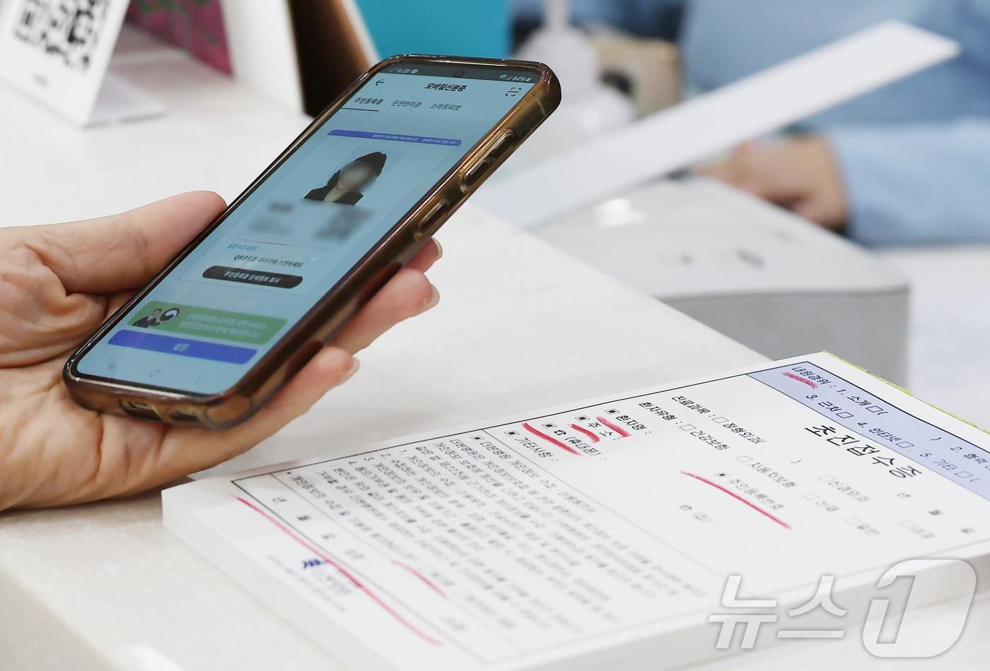 건강보험 본인확인 의무화 제도가 시행된 20일 오전 서울 동작구 한 병원에서 시민이 접수를 하며 모바일신분증을 보여주고 있다. 2024.5.20/뉴스1 ⓒ News1 김민지 기자
