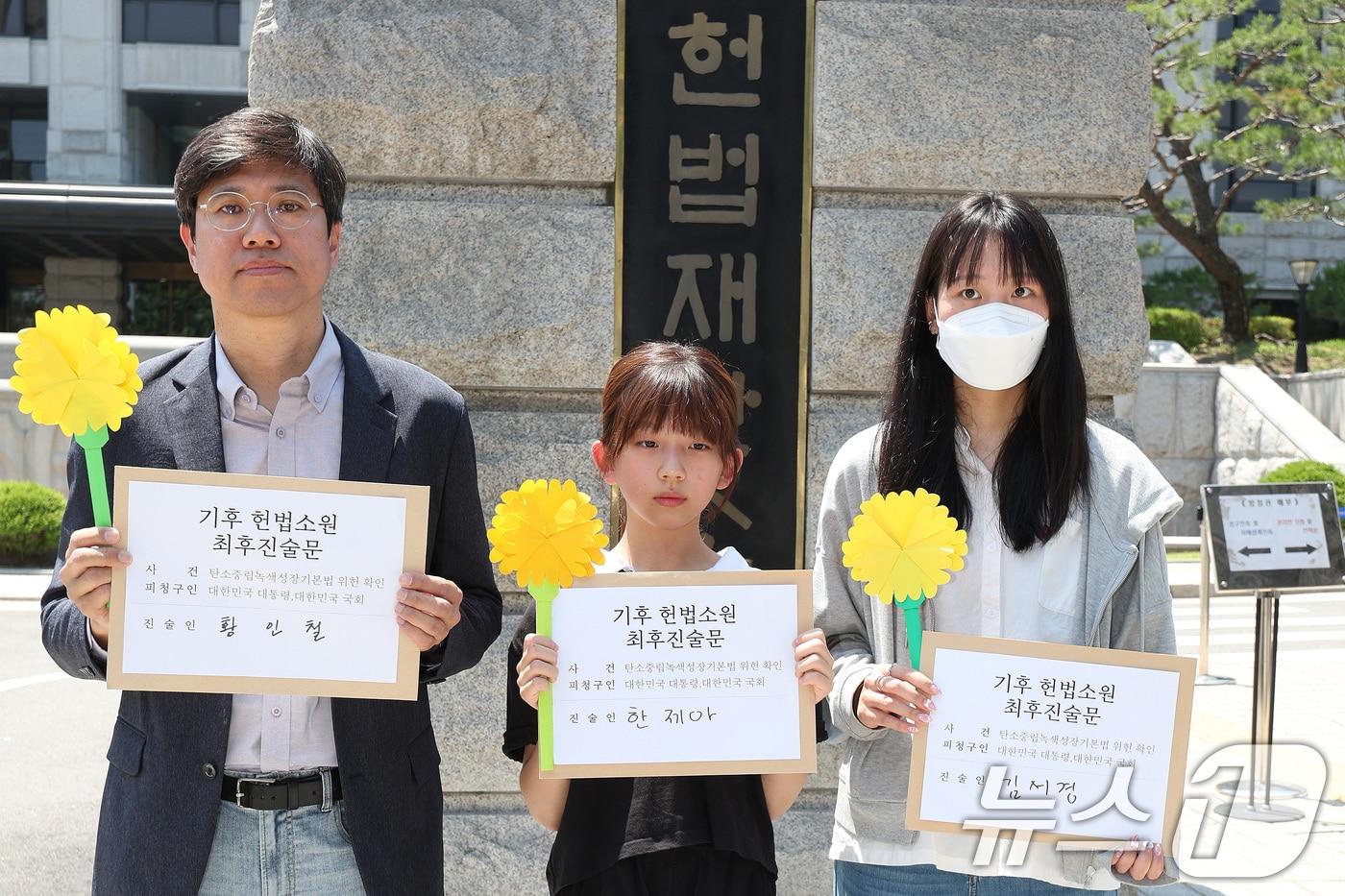 본문 이미지 - 서울 종로구 헌법재판소 앞에서 기후 헌법소원의 마지막 공개변론을 앞두고 열린 환경단체 기자회견에서 시민기후소송 청구인인 황인철 씨(왼쪽부터), 청소년기후소송 청구인 김서경 씨, 아기기후소송 청구인 한제아 양이 최후진술문을 들고 있다. 2024.5.21/뉴스1 ⓒ News1 신웅수 기자