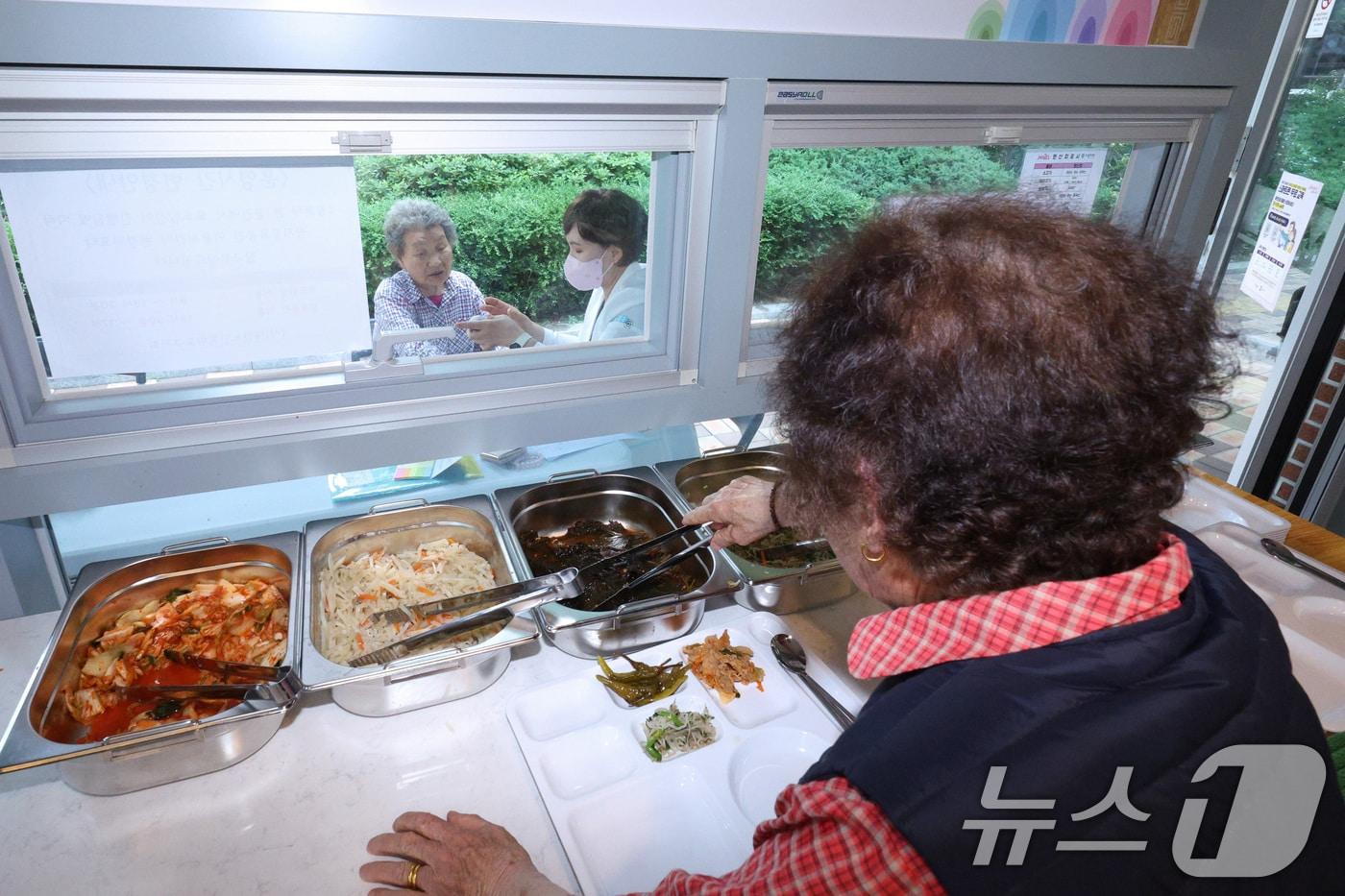서울 마포구 효도밥상경로당에서 열린 주민참여 효도밥상 제공 행사에 참가한 어르신들이 건강 검진 후 점심 식사를 배식받고 있다. 2024.5.21/뉴스1 ⓒ News1 신웅수 기자