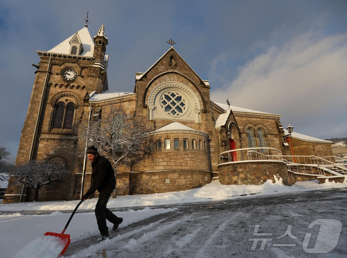본문 이미지 - 영국 스코틀랜드 피틀로치리에 있는 스코틀랜드 교회에서 한 남자가 눈을 치우고 있다. 2022.12.17/ ⓒ 로이터=뉴스1 ⓒ News1 권진영 기자