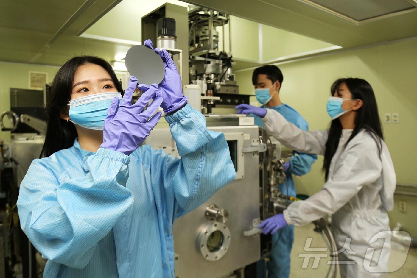 연구원들이 고진공상태의 OLDE 증착 장비에 OLED 소자를 넣기 위해 확인을 하고 있는 모습.(단국대 제공)