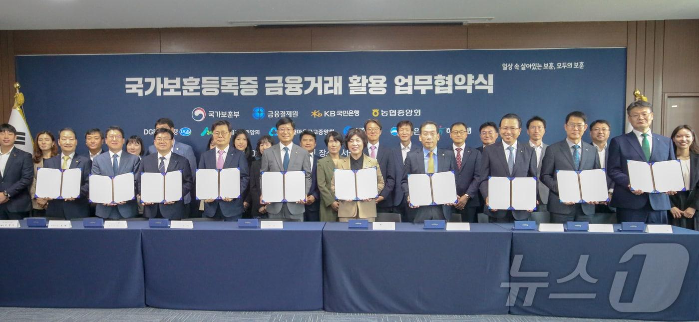 본문 이미지 - 강정애 국가보훈부 장관이 23일 오전 서울시 용산구 서울지방보훈청에서 열린 국가보훈등록증 진위확인서비스 업무협약식에 참석하여 박종석 금융결제원장, 김범석 우리은행 부행장 등 8개 금융기관 대표자들과 함께 협약식에 서명후 기념촬영을 하고 있다. (국가보훈부 제공) 2024.5.23/뉴스1