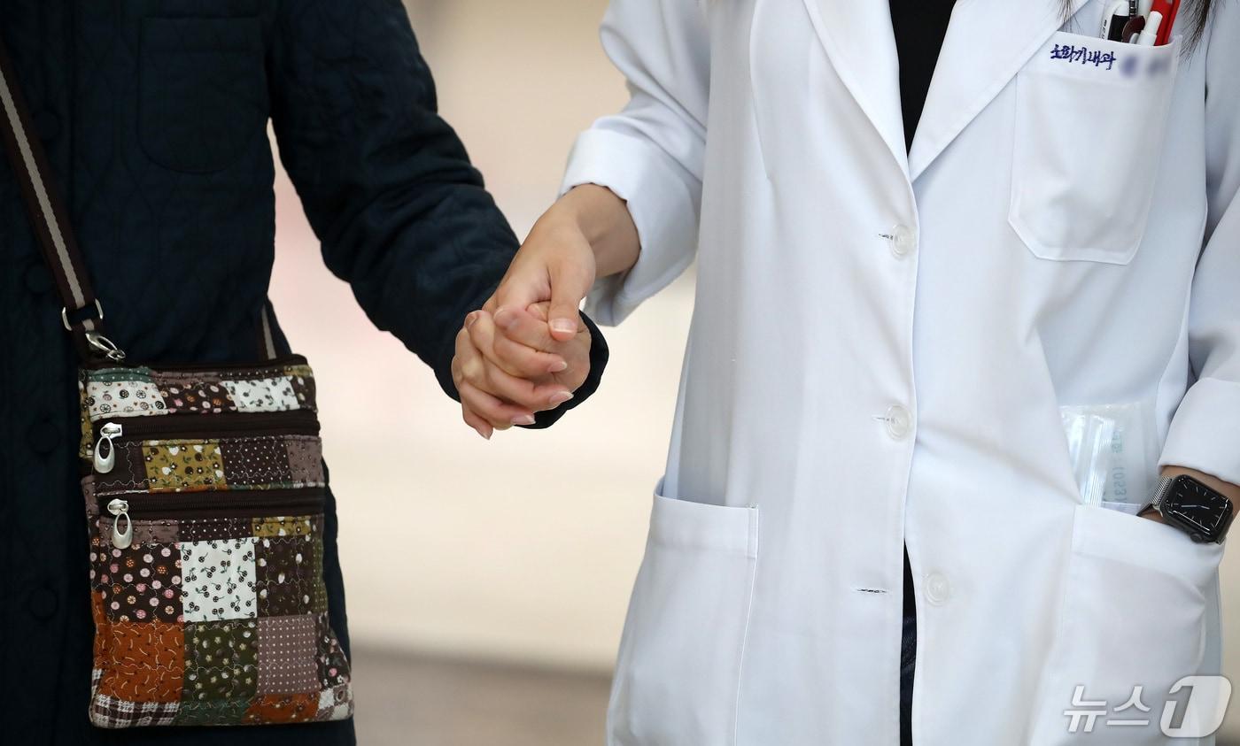 본문 이미지 - 3일 대구의 한 대학병원에서 의료진이 환자의 손을 잡고 걸어가고 있다.  (사진은 기사 내용과 무관함) / ⓒ 뉴스1 공정식 기자