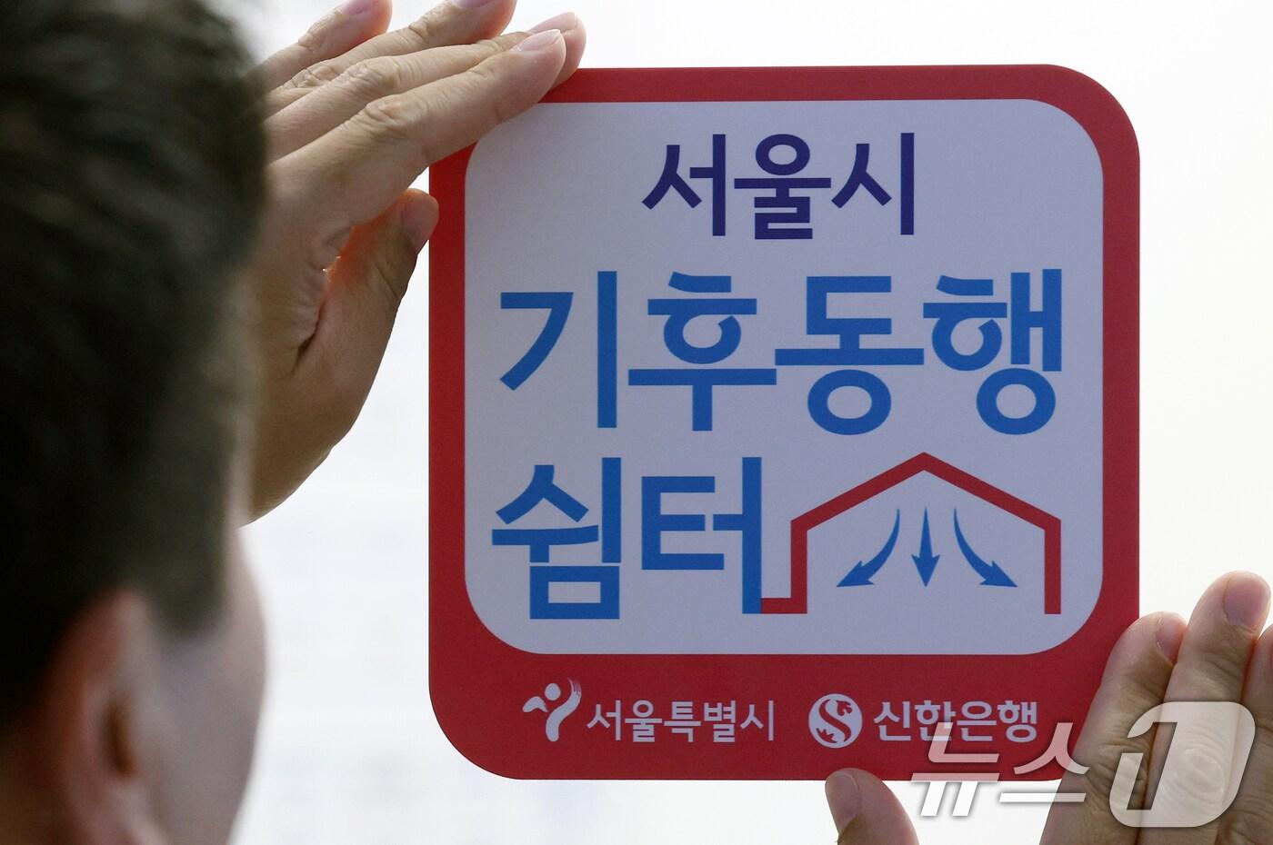 은행 직원이 '기후동행쉼터' 현판을 부착하고 있다.  2024.5.30/뉴스1 ⓒ News1 박정호 기자