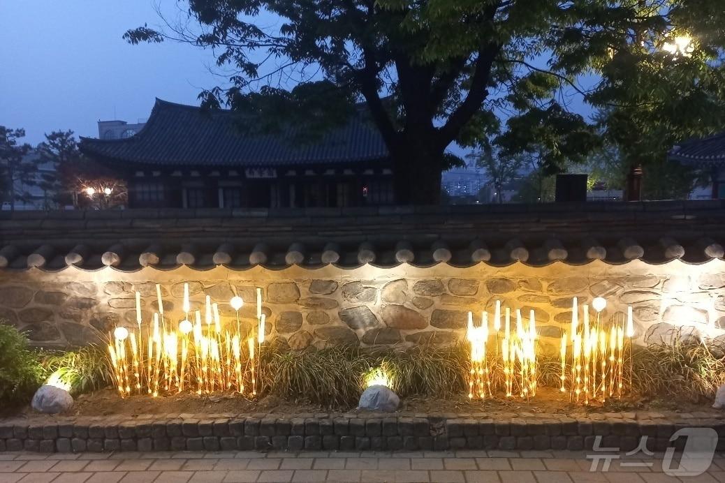 본문 이미지 -  7일 충북 충주시가 관아공원과 옛 조선식산은행을 빛으로 잇는 경관조명을 설치했다고 밝혔다. 사진은 관아공원 담장을 따라 조성한 담빛길 모습.(충주시 제공)2024.5.7/뉴스1