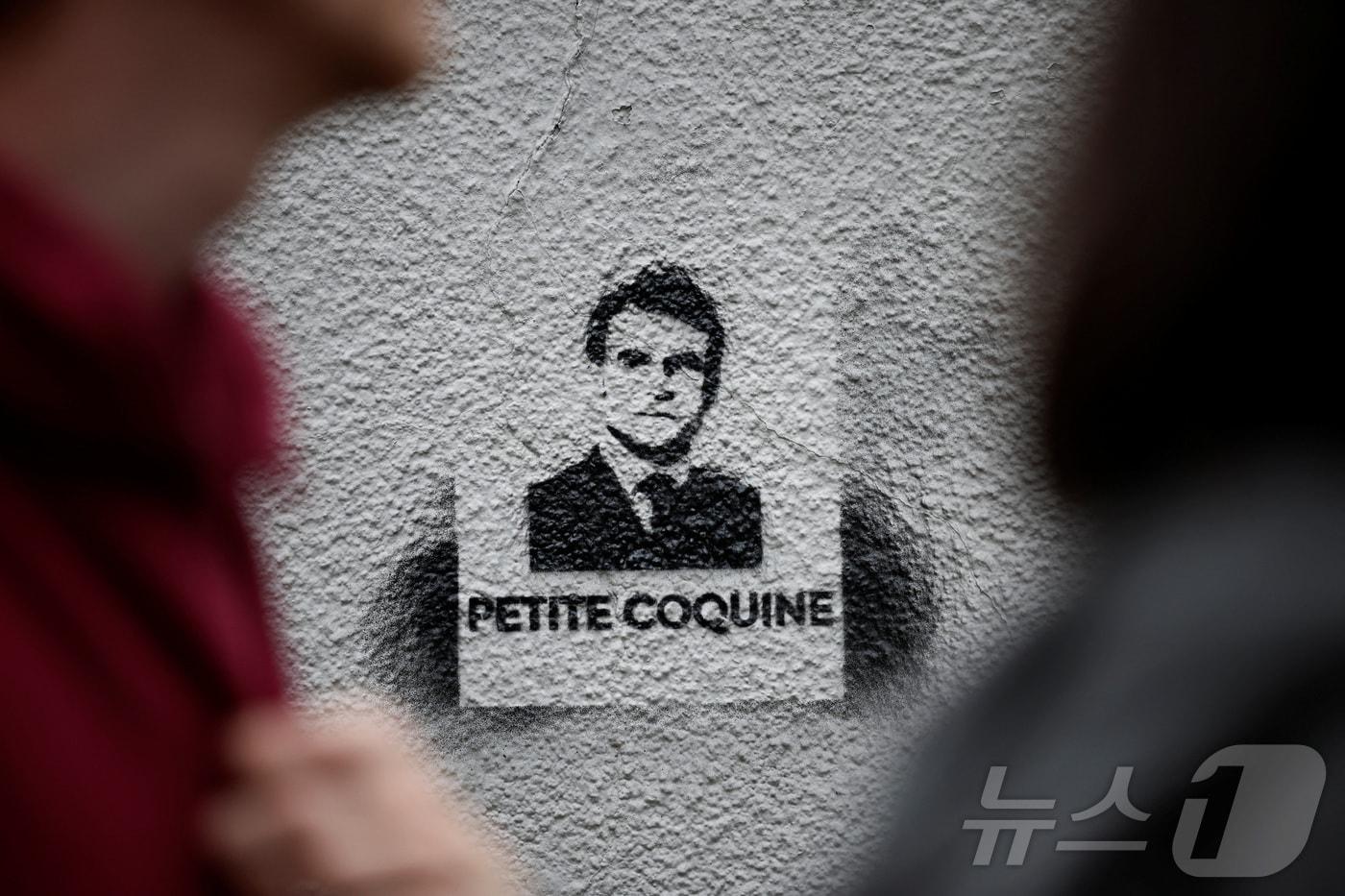 본문 이미지 - 프랑스 조기 총선을 앞두고 극우 성향의 정당 국민연합(RN) 반대 시위가 15일(현지시간) 파리에서 열린 가운데, 에마뉘엘 마크롱 대통령 얼굴 그림 밑으로 "나쁜 놈＂이라는 문구가 쓰여진 벽화를 시민들이 지나치고 있다. 2024.06.16. ⓒ 로이터=뉴스1 ⓒ News1 김민재 기자