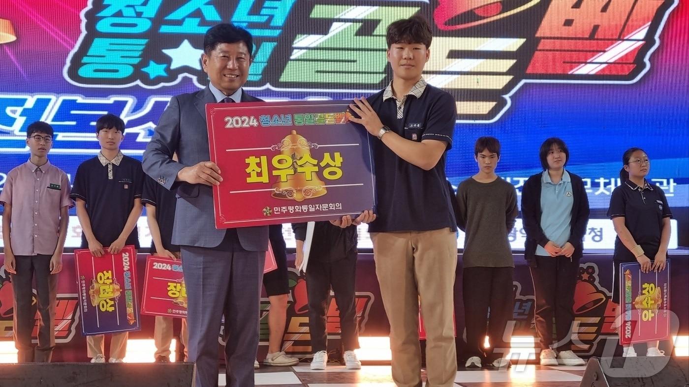 18일 대전 충무체육관에서 열린 ‘2024 청소년 통일 골든벨’ 시상식에서 김동원 민주평화통일자문회의 대전부의장(왼쪽)이 고주몽 군에게 최우수상을 수여한 뒤 기념촬영을 하고 있다. (민주평통 대전지역회의 제공) /뉴스1