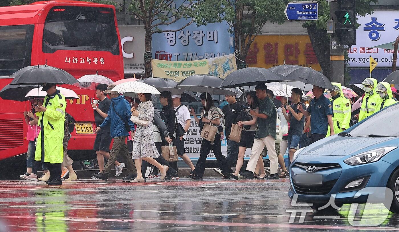 본문 이미지 - 더위를 식혀주는 비가 내린 22일 오전 서울 숭례문 인근에서 시민들과 외국인 관광객들, 경찰이 우산을 쓰고 이동하고 있다, 2024.6.22/뉴스1 ⓒ News1 김진환 기자