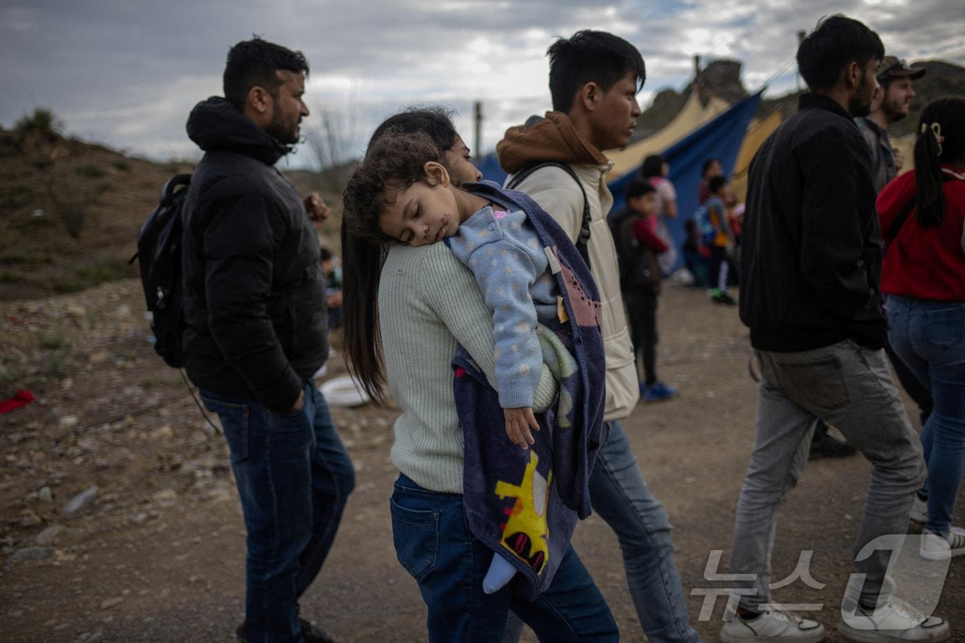 본문 이미지 - 인도에서 온 이민자 여성이 지난해 6월 25일(현지시간) 딸을 안은 채 멕시코에서 미국으로 국경을 따라 걸어가고 있다. 2024.06.25 ⓒ 로이터=뉴스1 ⓒ News1 임여익 기자