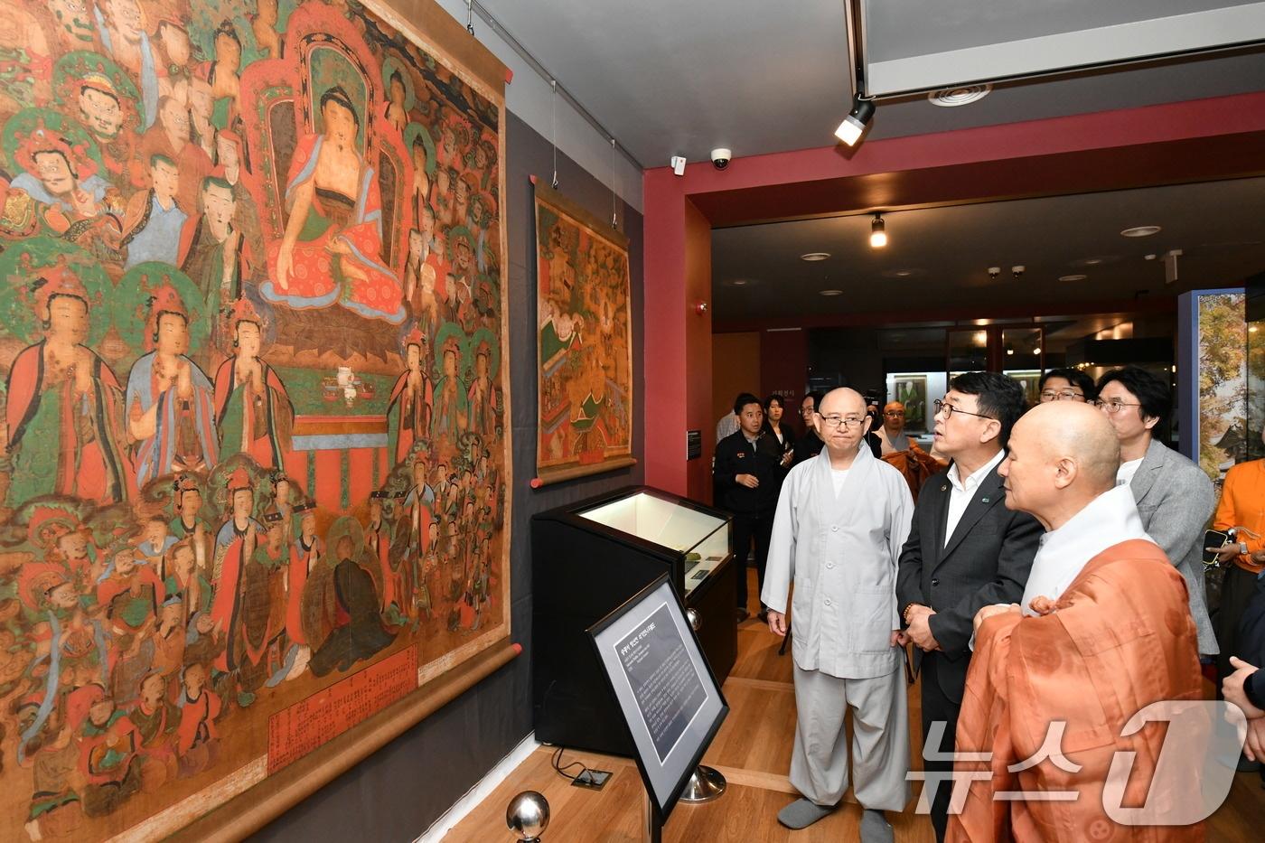 최응천 국가유산청장(가운데)이 27일 오후 전라남도 순천 송광사 성보박물관에서 국보로 지정된 ‘순천 송광사 영산회상도 및 팔상도’ 중 영산회상도를 살펴보고 있다. 국가유산청 출범 후 첫 국보 지정 사례인 ‘순천 송광사 영산회상도 및 팔상도’는 영산회상도 1폭과 팔상도 8폭으로 구성됐다.(국가유산청 제공) 2024.6.27/뉴스1