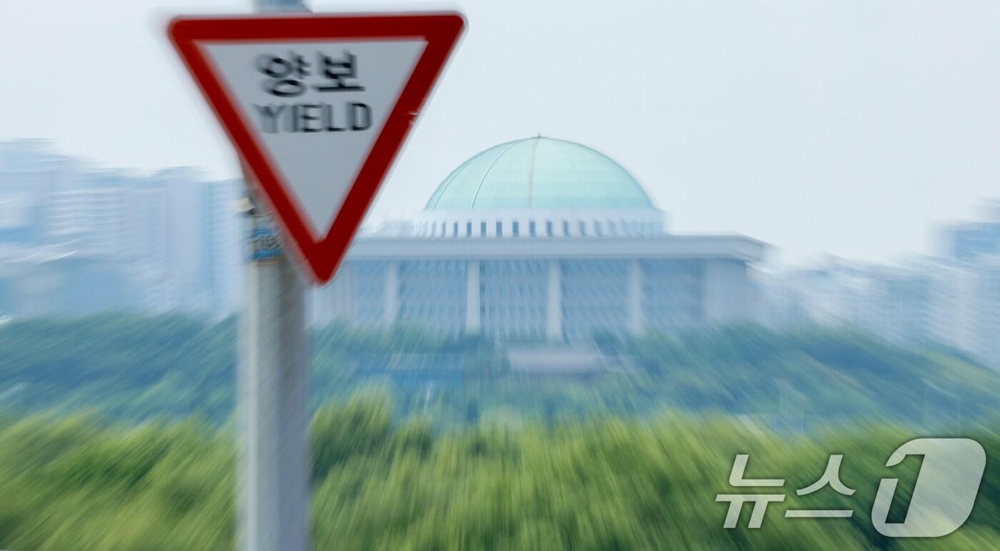 본문 이미지 - 여야가 원구성 협상의 합의점을 찾지 못하고 있는 9일 서울 서강대교에 있는 양보 교통표지판 뒤로 국회의사당이 보이고 있다. 더불어민주당은 이날까지 합의에 이르지 못할 경우 10일 본회의를 열어 야당 단독으로 법제사법위원회·운영위원회·과학기술정보방송통신위원회를 포함한 11개 상임위원장을 선출하겠다고 예고했다. 2024.6.9/뉴스1 ⓒ News1 안은나 기자