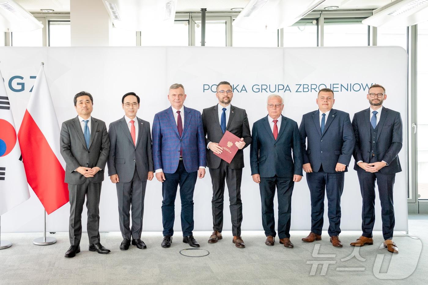 본문 이미지 - 지난 9일(현지시간) 폴란드에서 진행된 신규 컨소시엄 합의서 체결식에서 양국 정부 및 기업 관계자들이 기념 촬영을 하고 있다. 사진 왼쪽부터 임훈민 주폴란드 대한민국 대사관 대사, 이용배 현대로템 대표이사 사장, 파베우 베이다 폴란드 국방차관, 마르친 쿨라섹 폴란드 국유재산부 차관, 크리스토프 트로피니악 PGZ 회장.(현대로템 제공) 