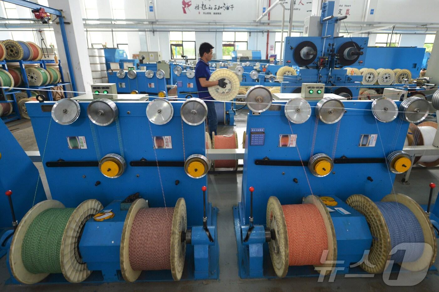 중국 저장성 후저우에 있는 저장헤드웨이 통신장비 공장에서 한 직원이 광섬유 케이블을 생산하는 생산 라인에서 일하고 있다.2019.5.15/ ⓒ 로이터=뉴스1 ⓒ News1 이강 기자