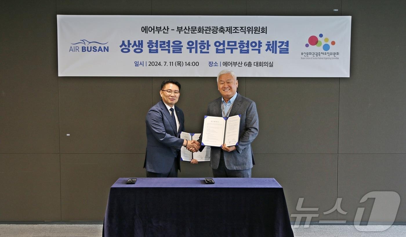 11일 마호진 에어부산 영업본부장(왼쪽)과 고인범 부산문화관광축제조직위원회 집행위원장이 업무협약을 체결하고 기념촬영을 하고 있다.(에어부산 제공)