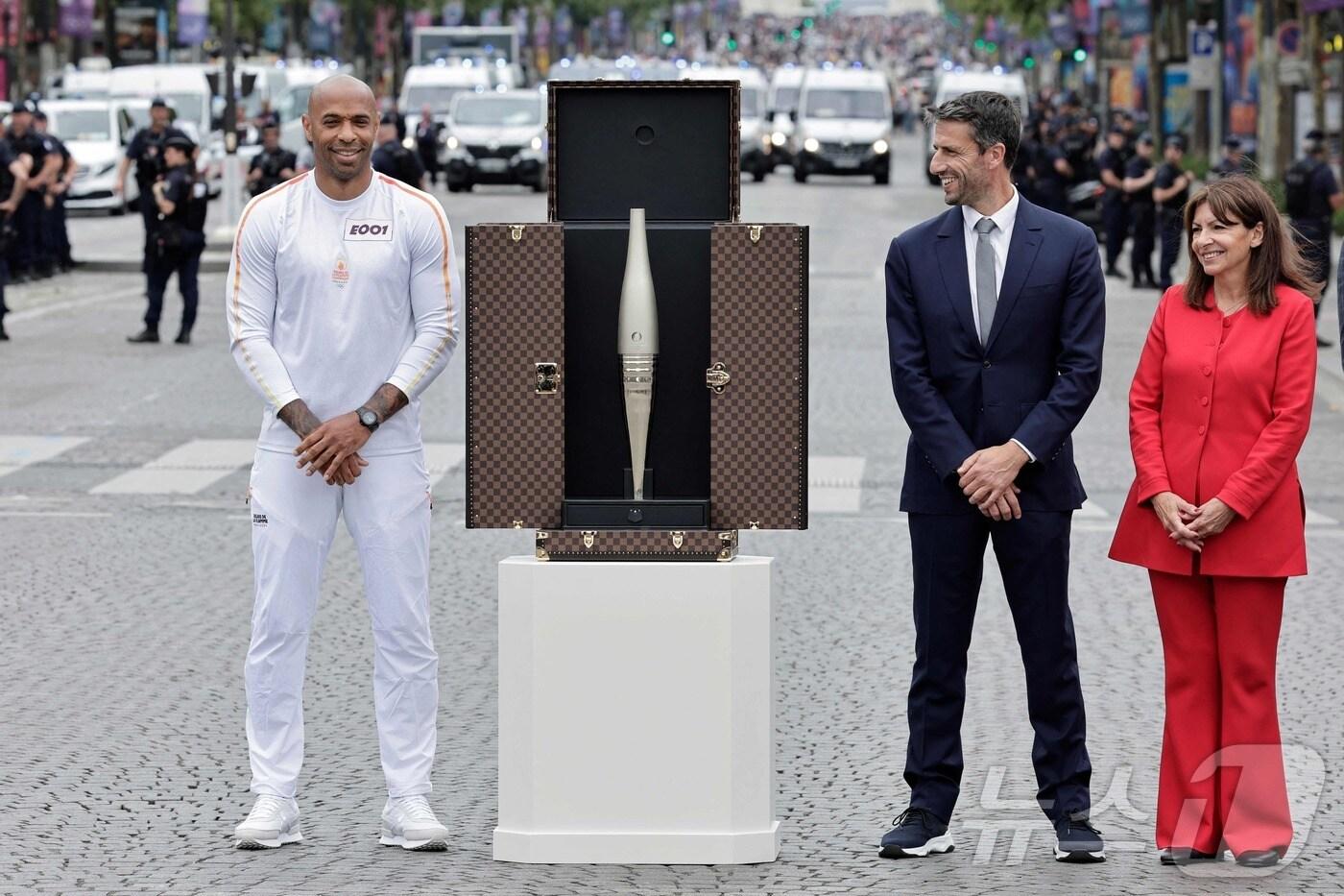 티에리 앙리 프랑스 올림픽 축구대표팀 감독과 앤 히달고 파리 시장(오른쪽)이 14일 바스티유 군사퍼레이드가 펼쳐지는 상젤리제 거리 한편에서 파리 올림픽 협찬사인 루이뷔통 모네 헤네시(LVMH)가 제작한 성화 가방을 선보이고 있다. 2024.07.14 ⓒ AFP=뉴스1 ⓒ News1 강민경기자