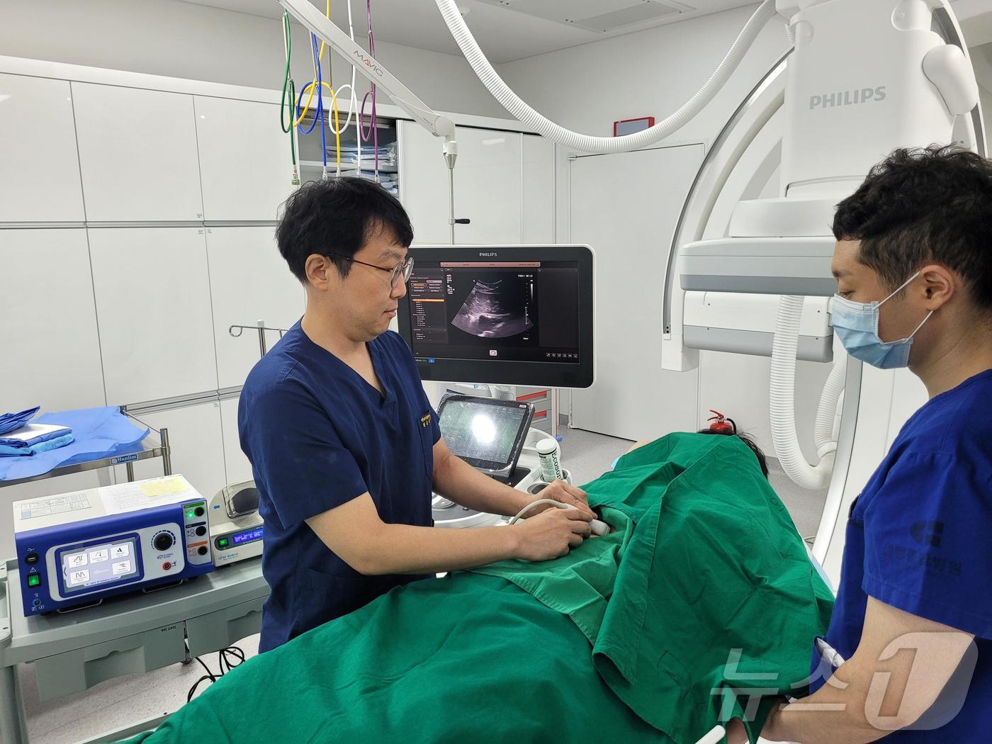 본문 이미지 - 센텀종합병원 영상의학과 손일완(왼쪽) 과장이 ‘고주파 열 치료’ 시술을 진행하고 있다.(센텀종합병원 제공)