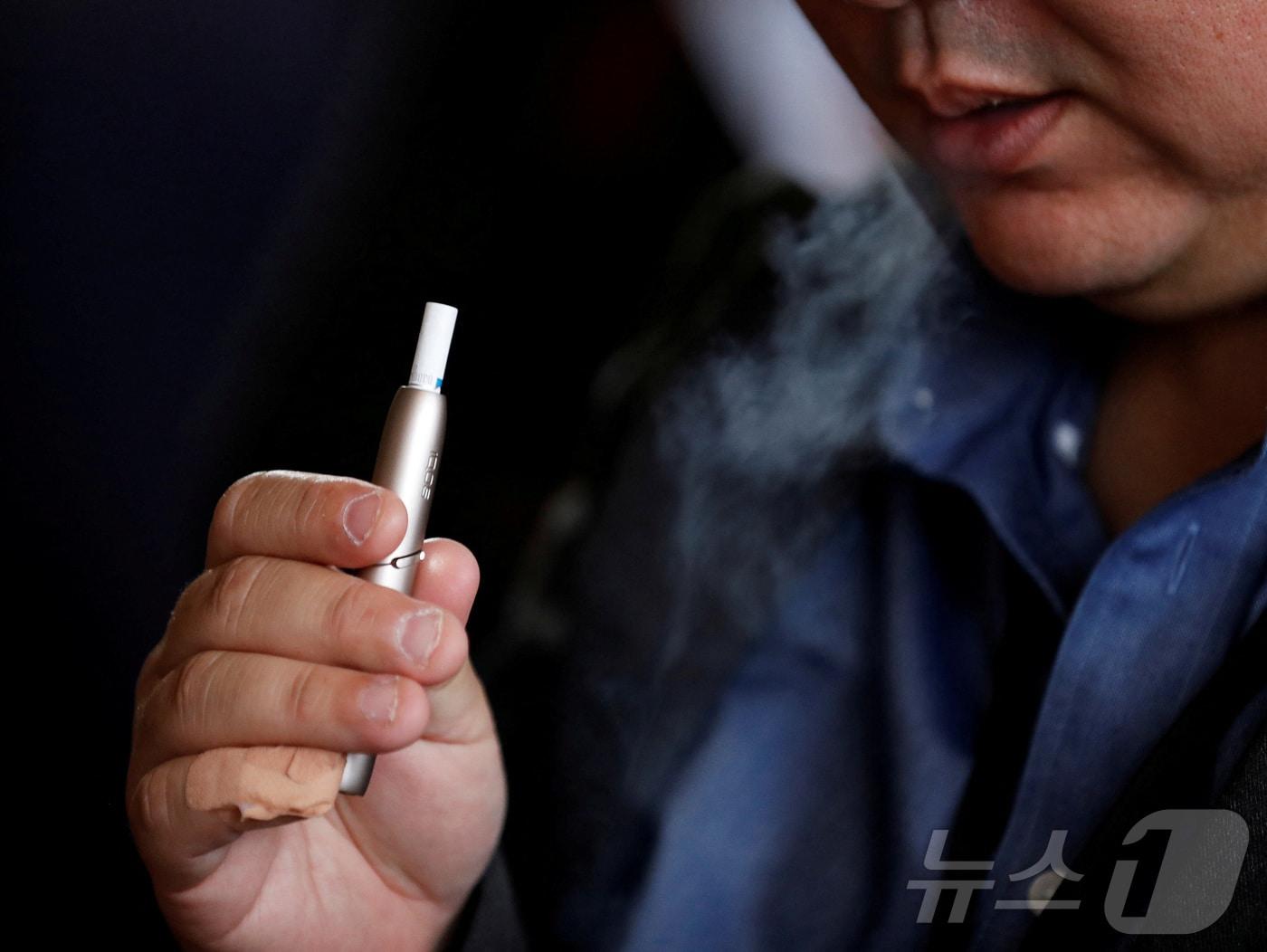 본문 이미지 - 2018년 10월 일본 도쿄에서 필립모리스가 궐련형 전자담배 '아이코스3' 출시 행사를 열자 한 시민이 이를 태우고 있다<자료사진>. 2018.10.23. ⓒ 로이터=뉴스1 ⓒ News1 김성식 기자
