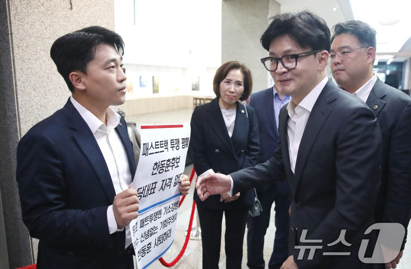 본문 이미지 - 한동훈 국민의힘 당대표 후보가 18일 오후 서울 중구 서울시의회에서 열린 국민의힘 서울시의회 의원간담회 회의장 앞에서 '패스트트랙 투쟁 폄훼 한동훈 후보 당대표 자격 없다'가 적힌 피켓을 든 이희원 서울시의원(국민의힘)과 이야기를 나누고 있다. 2024.7.18/뉴스1 ⓒ News1 임세영 기자