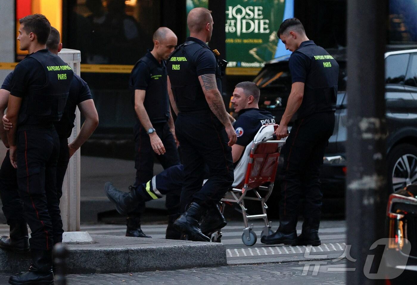 본문 이미지 - 18일(현지시간) 프랑스 파리 샹젤리제 거리에 한 경찰관이 부상을 입고 휠체어에 앉아있다. (사진은 기사 내용과 무관함) / 뉴스1 ⓒ News1 2024.07.18. ⓒ 로이터=뉴스1 ⓒ News1 장시온 기자