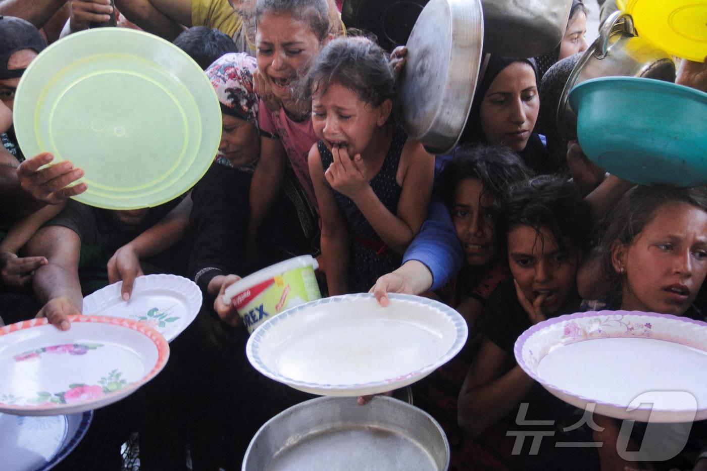 본문 이미지 - 가자지구 북부의 한 식당에 팔레스타인 어린이들이 음식을 받기 위해 모여 있다. 2024.07.18. ⓒ 로이터=뉴스1 (자료사진)