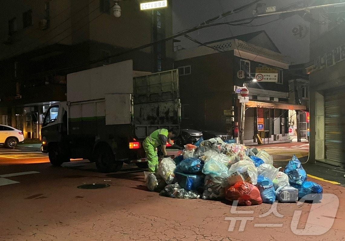 본문 이미지 - 18일 밤 서울 성동구 용답동 용답시장 인근 골목에서 쓰레기봉투를 차에 싣고 있는 환경미화원의 모습. 2024.7.18
