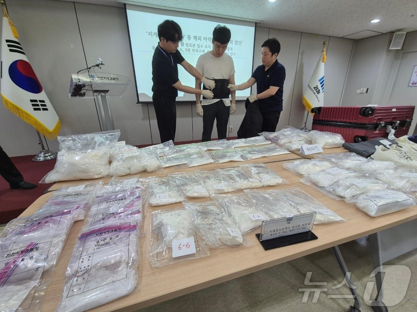 본문 이미지 - 캄보디아에서 인천국제공항을 통해 밀반입된 필로핀과 케타민등 마약으로 71만 명이 동시 투약할 수 있다. 검찰 관계자들이 복대에 마약을 숨기는 방식을 재현하고 있다.ⓒ News1 이시명 기자