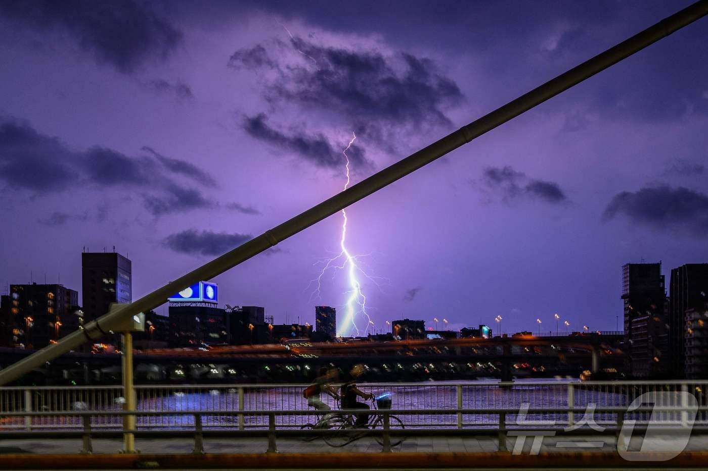 일본 도쿄에서 사람들이 번개 치는 밤, 신오하시 다리 위를 건너가고 있다. 2024.07.22/ ⓒ AFP=뉴스1 ⓒ News1 권진영 기자