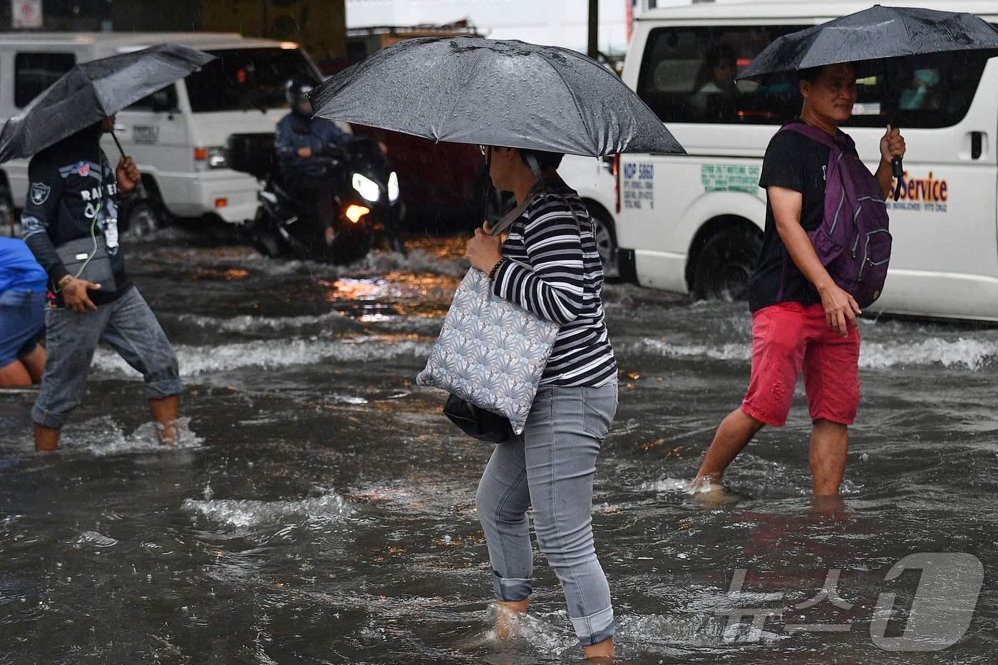 필리핀 마닐라 시민들이 23일 3호 태풍 '개미'가 몰고온 폭우로 물이 차오른 마닐라 거리를 걷고 있다. 2024.07.23 ⓒ AFP=뉴스1 ⓒ News1 권진영기자