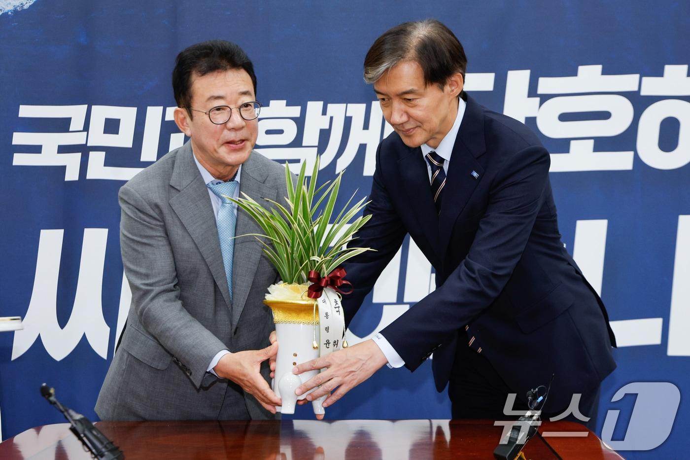 조국 조국혁신당 대표(오른쪽)가 25일 오전 서울 여의도 국회에서 홍철호 대통령실 정무수석으로부터 윤석열 대통령이 보낸 취임 축하 난을 전달받고 있다. 2024.7.25/뉴스1 ⓒ News1 안은나 기자