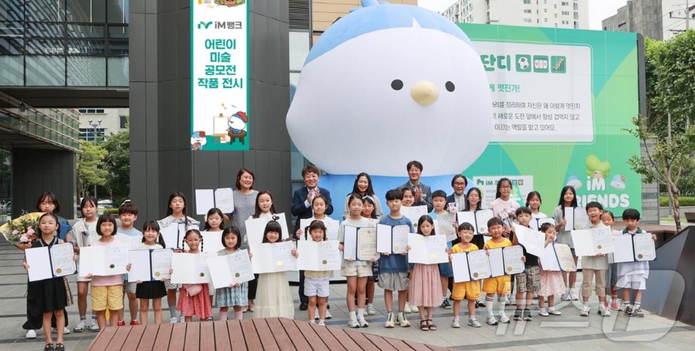 본문 이미지 - 제20회 iM뱅크 어린이 미술 공모전 수상자들이 iM뱅크 1본점 광장에서 기념사진을 찍고 있다.&#40;iM뱅크 제공&#41;