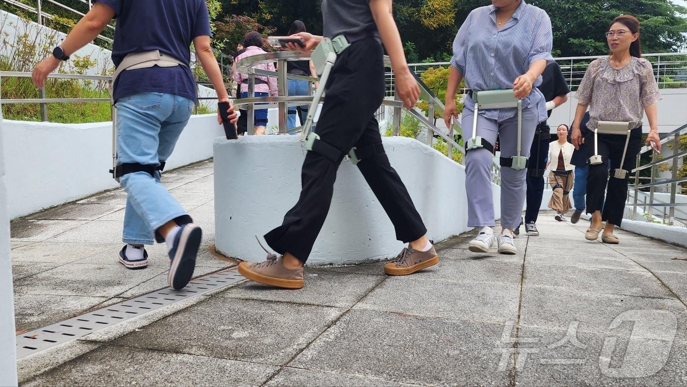 시니어 운동 지원 관계자들이 지난 2일 천안시청에서 열린 보행보조 로봇 체험행사에서 위로보틱스가 개발한 '윔'을 착용한 채 산책하고 있다. 2024.7.2. /뉴스1ⓒNews1 이시우 기자