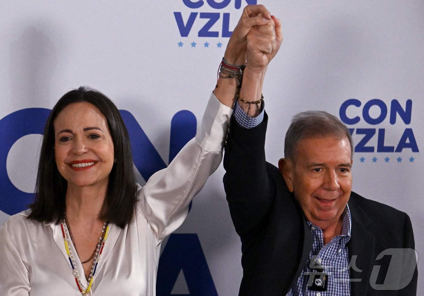 베네수엘라 대선 하루 뒤인 29일(현지시간) 베네수엘라 야당 대표 마리아 코리나 마차도(왼쪽)가 같은 당 대선 후보 에드문도 곤살레스 우루티아와 함께 손을 들어올리고 있다. 이날 니콜라스 마두로 대통령이 대선에서 승리했다는 결과가 발표되자 베네수엘라 카라카스 곳곳에서 저항하는 시위가 벌어졌다. 2024.07.29. ⓒ AFP=뉴스1 ⓒ News1 김종훈 기자