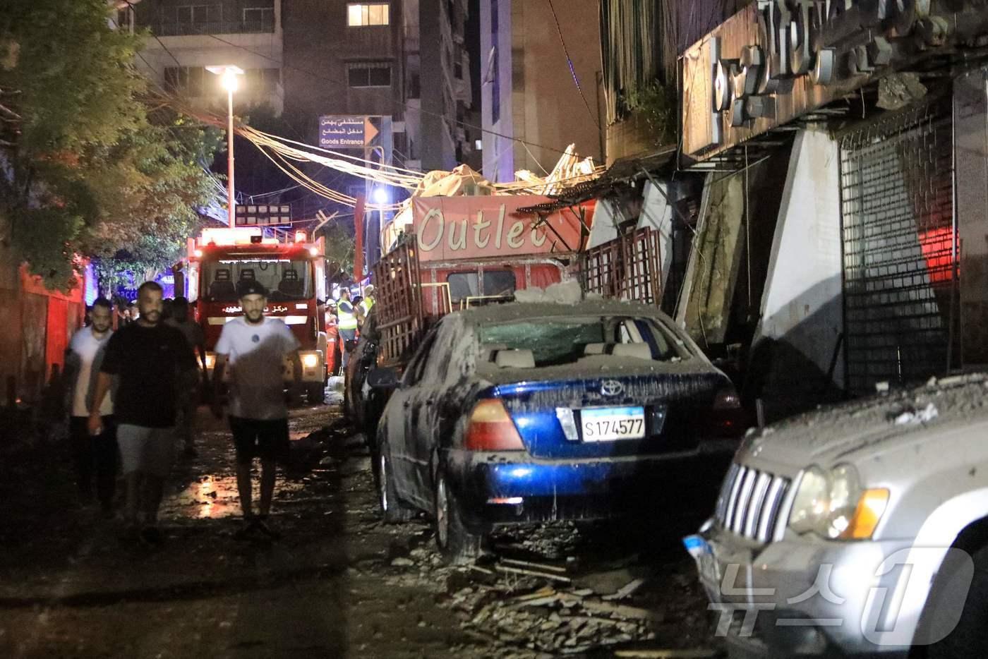 본문 이미지 - 30일(현지시간) 이스라엘이 레바논 베이루트의 남부 교외 지역을 공습한 뒤 부서진 건물 잔해 옆으로 시민들이 지나고 있다. 이날 이스라엘군은 골란고원에서 어린이 사망자를 낸 로켓공격에 책임이 있는 헤즈볼라 사령관이 공습 목표였다고 밝혔다. 2024.07.30. ⓒ AFP=뉴스1 ⓒ News1 김종훈 기자