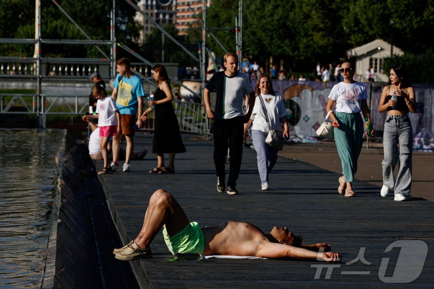 본문 이미지 - 2일(현지시간) 러시아 모스크바의 한 공원에서 더운 날씨에 한 남성이 웃옷을 벗은 채 분수 옆에 드러누워 있다. 2024.07.02 ⓒ 로이터=뉴스1