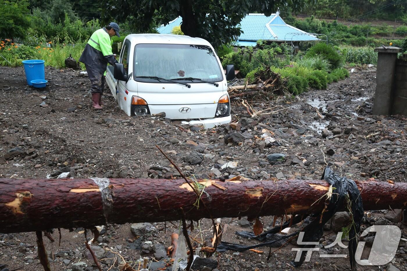 본문 이미지 - 8일 오후 경북 영양군 입암면 금학리 한 주택에서 주민 이명섭씨(73)가 집중호우로 뒷산에서 쏟아진 토사에 갇힌 트럭을 살펴보고 있다.  2024.7.8/뉴스1 ⓒ News1 공정식 기자