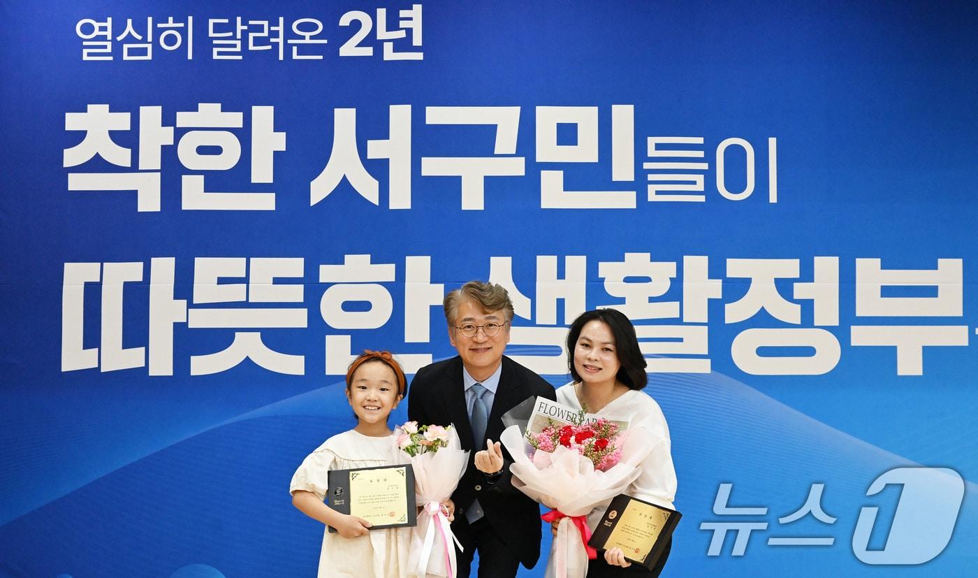 김이강 광주 서구청장이 1일 김수현 어린이(왼쪽)와 광주서구가족센터 원가빈 씨(오른쪽)에게 구정발전 유공 표창을 수여한 뒤 기념촬영하고 있다.(광주 서구 제공) 2024.8.1/뉴스1 