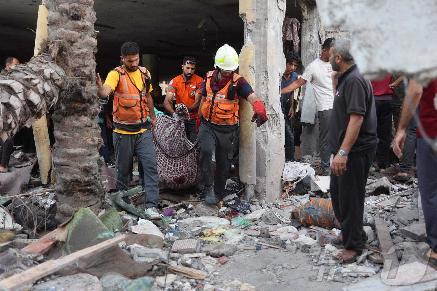 본문 이미지 - 10일(현지시간) 가자지구 가자시티의 한 학교에서 구조대원들이 이스라엘의 로켓 공격으로 사망한 희생자를 수습하고 있다. 2024.08.10/ ⓒ AFP=뉴스1 ⓒ News1 권진영 기자