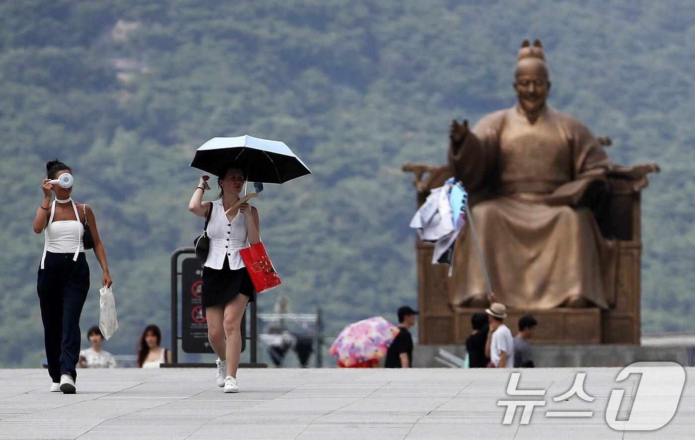 전국 대부분 지역에 폭염특보가 발효된 가운데 13일 오후 서울 종로구 광화문광장에서 외국인 관광객들이 휴대용 선풍기로 더위를 식히며 걷고 있다.  ⓒ News1 오대일 기자