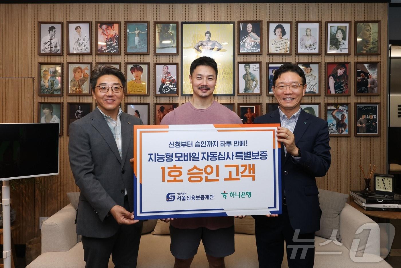 2일 서울 강남 논현동 '잭스 피트니스'에서 자동심사 특별보증 1호 고객인 김재근 대표(가운데)가 주성원 서울신용보증재단 부장(왼쪽), 장태융 하나은행 지점장(오른쪽)과 기념촬영을 하고 있다.(서울시 제공)