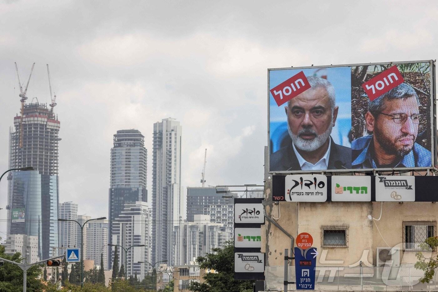 2일 이스라엘 텔아비브 시내 건물 광고판에 사망한 하마스 지도자 이스마일 하니예와 모하메드 데이프의 대형 사진이 걸려있다. 지명수배범처럼 내걸린 사진에는 빨간바탕에 히브리어로 '암살'이라 쓰인 낙인이 찍혀 있다. 이스라엘군은 1일 하마스 군사 지휘관 데이프가 지난달말 가자지구 남부에 가해진 공습에 사망한 것으로 확인됐다고 밝혔다. 2024.08.02 ⓒ AFP=뉴스1 ⓒ News1 김종훈기자