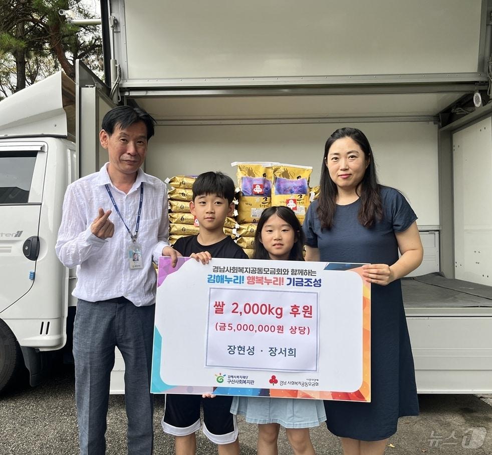 본문 이미지 - 지난 21일 김해 구산사회복지관을 찾은 장현성(왼쪽 두번째), 장서희 남매가 어려운 이웃을 돕기 위한 쌀 200포대를 기부하고 기념쵤영을 하고 있다.(김해시 제공)